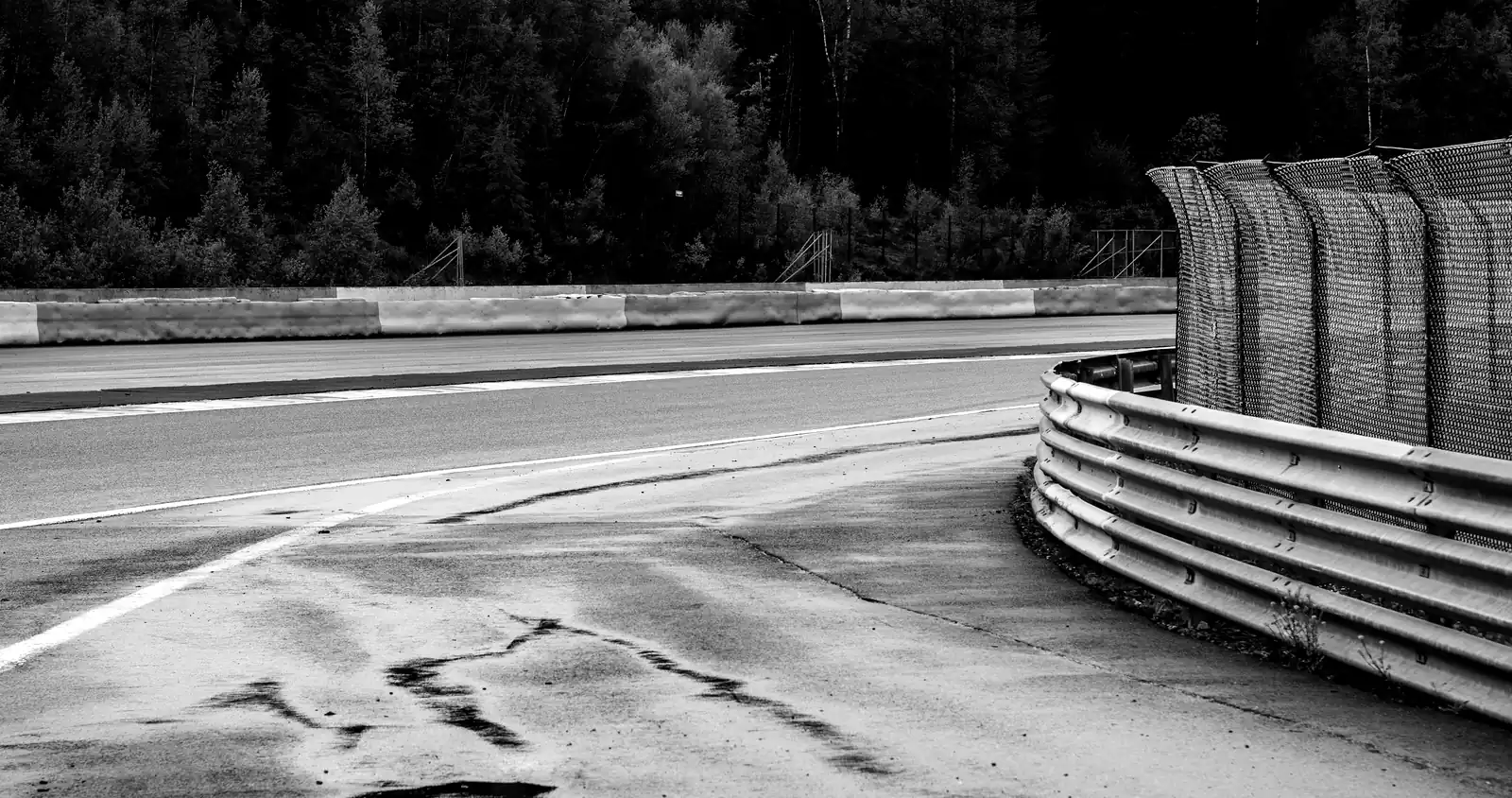 Virage de circuit détrempé, glissière de sécurité et traces de gomme sur l'asphalte